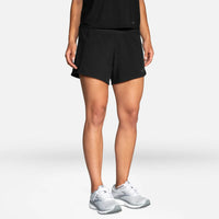 Person wearing black athletic shorts and white sneakers on a light gray background
