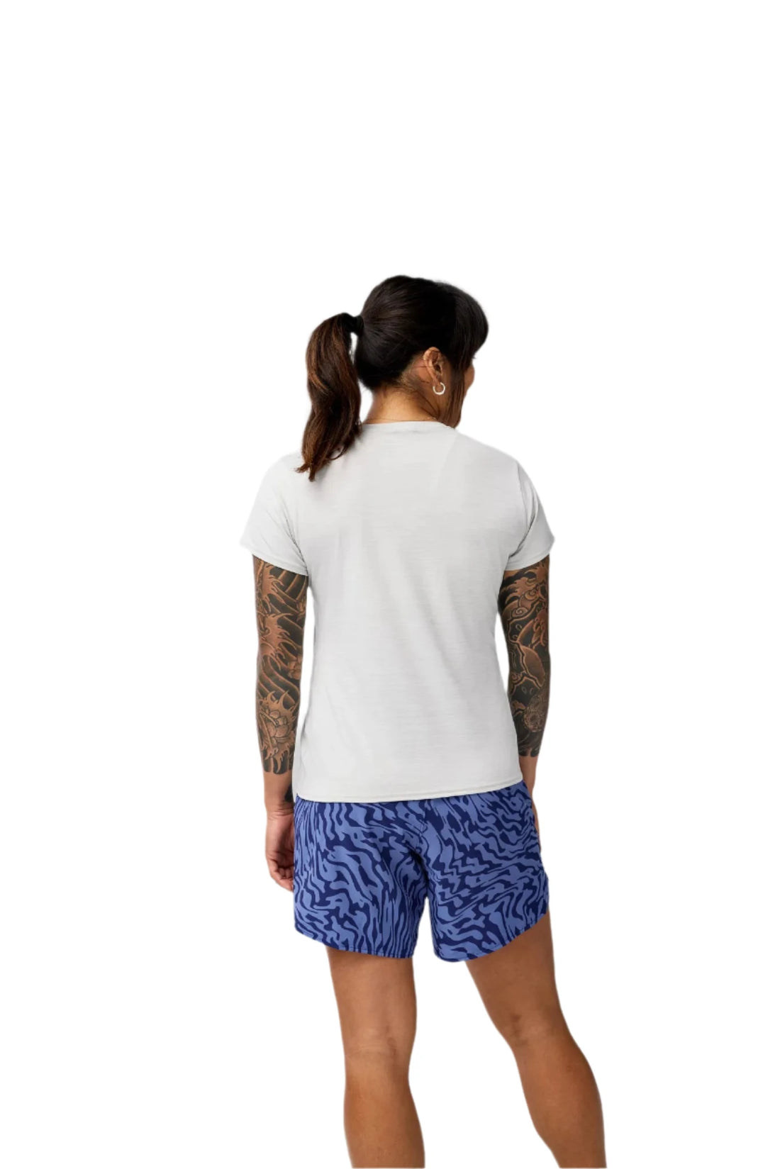 Person wearing a white t-shirt and blue patterned shorts on a plain background