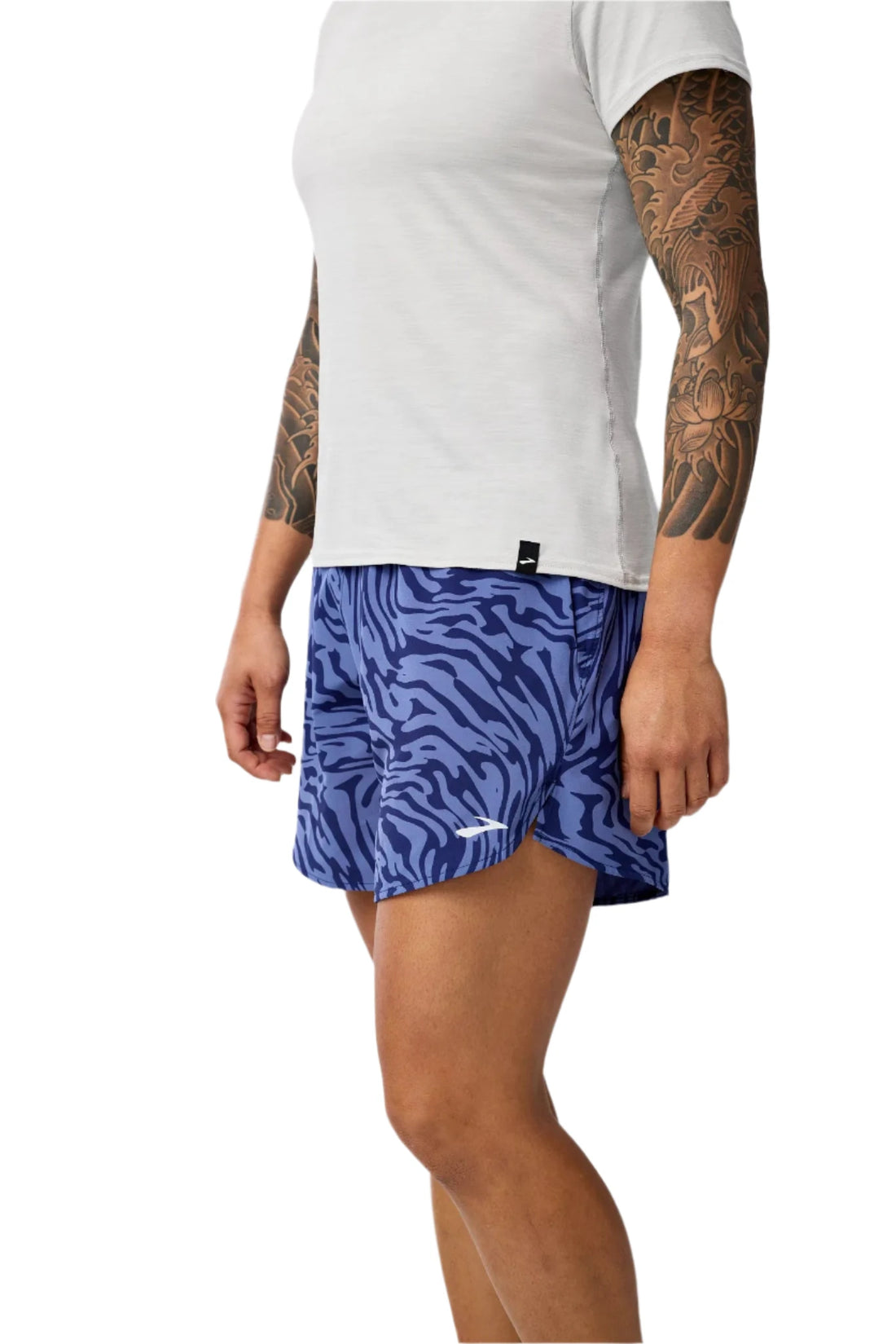 Person wearing blue patterned shorts and a white t-shirt on a plain background