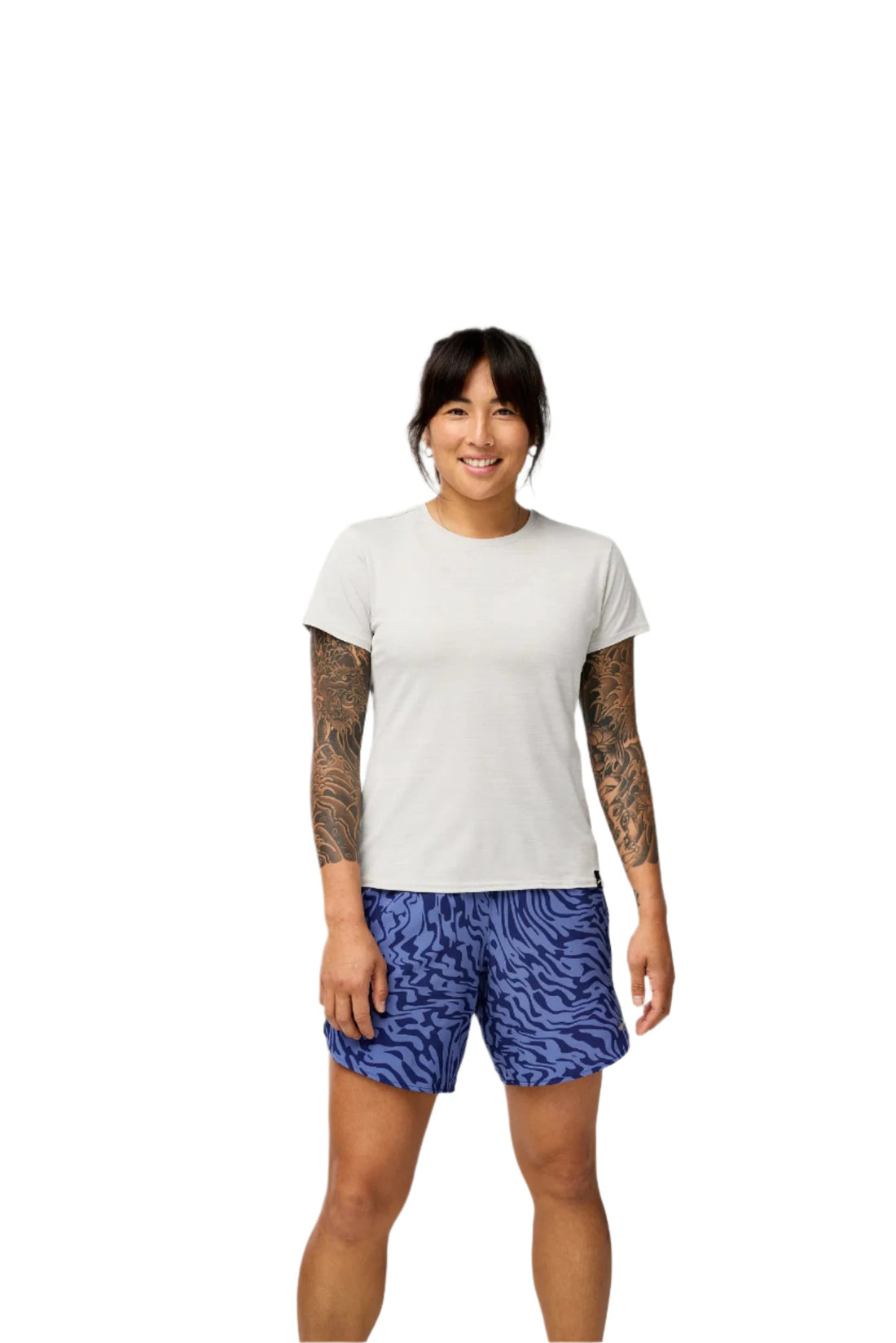 Person wearing a white t-shirt and blue patterned shorts on a plain background