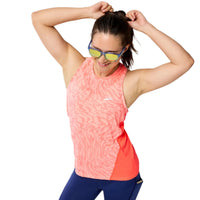 Woman wearing a pink and blue athletic outfit with sunglasses on a gray background