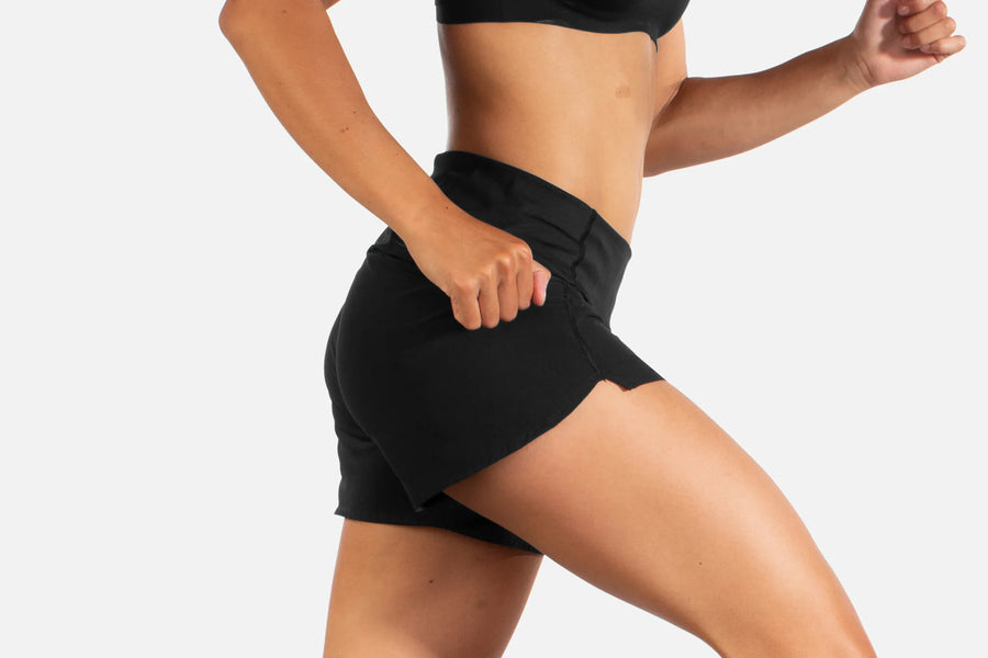 Person wearing black athletic shorts on a plain background