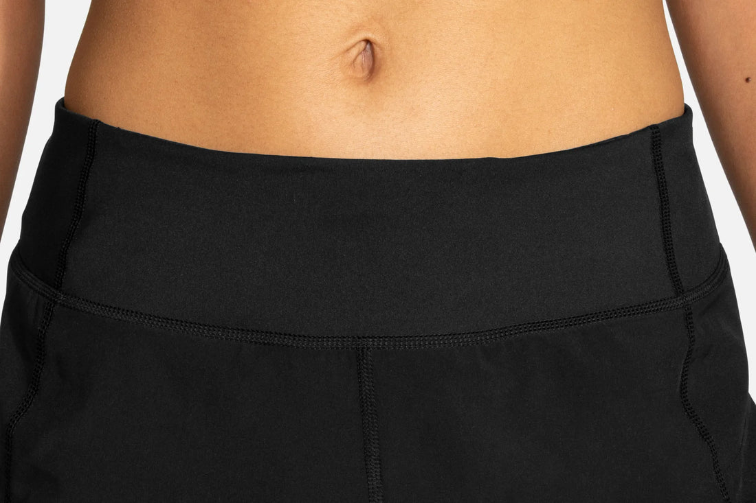 Close-up of a person wearing black pants with a neutral background