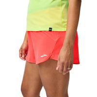 Person wearing a bright green shirt and red shorts on a plain background