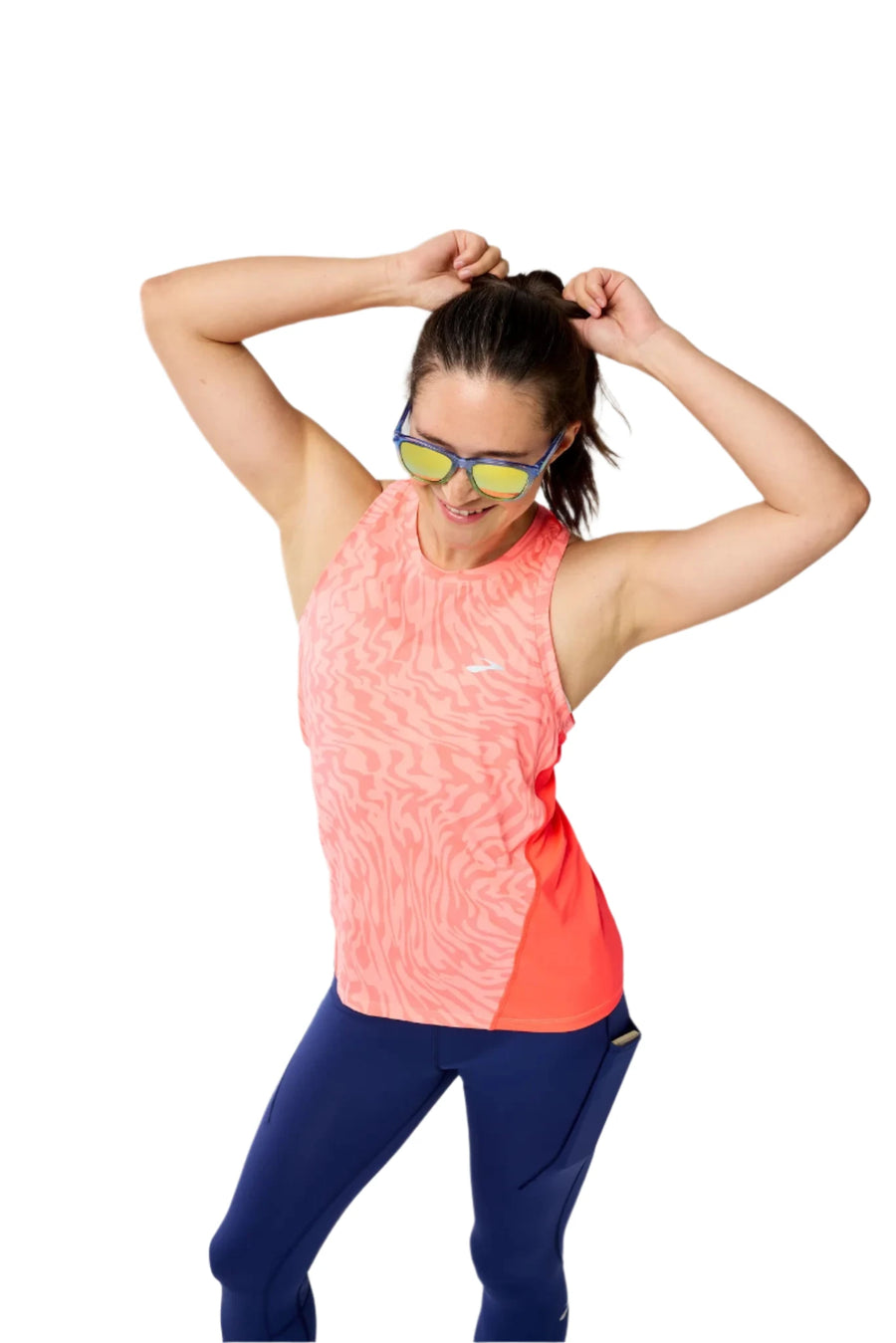 Woman wearing a pink and blue athletic outfit with sunglasses on a gray background