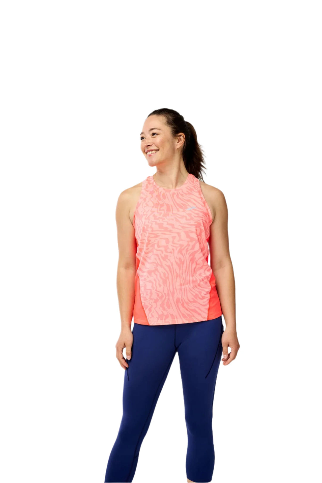 Woman wearing a pink sleeveless top and blue leggings on a gray background